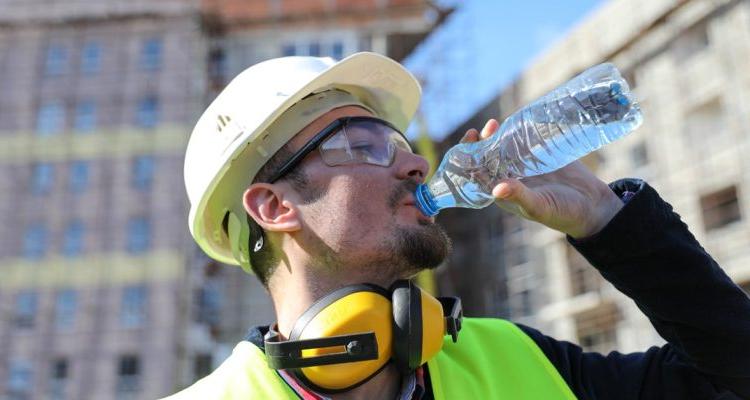 夏天，建筑工地的工人拿着一瓶水